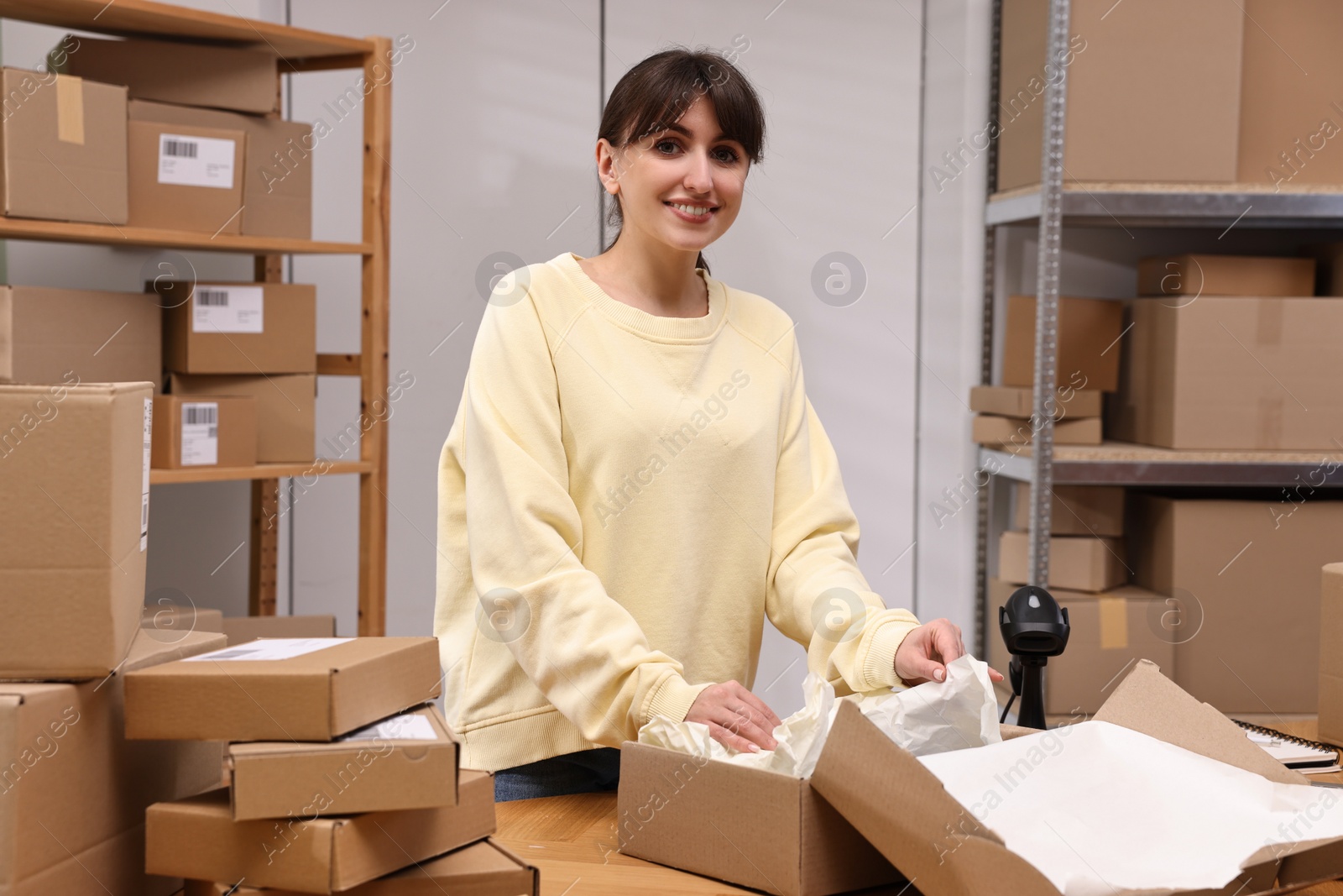 Photo of Post office worker packing parcel at wooden table indoors