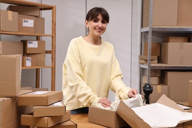 Photo of Post office worker packing parcel at wooden table indoors