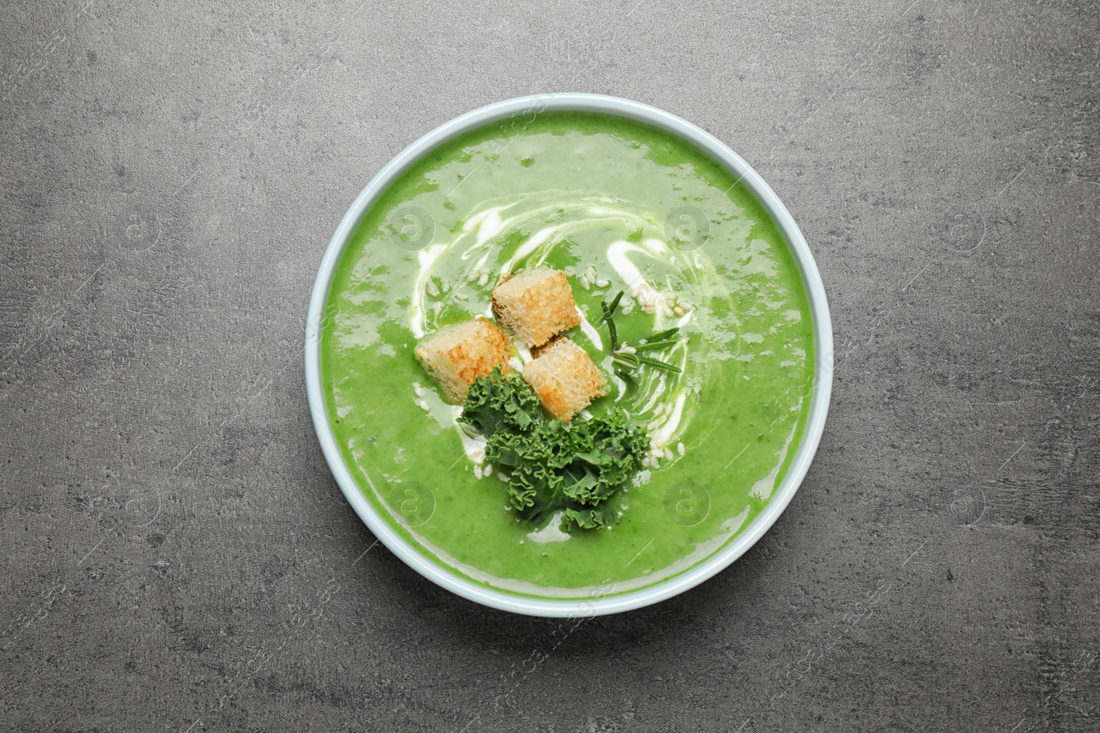 Photo of Tasty kale soup with croutons on grey table, top view