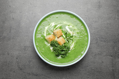 Photo of Tasty kale soup with croutons on grey table, top view