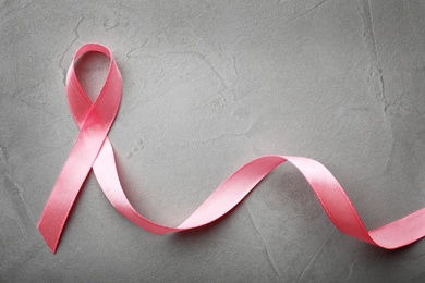 Photo of Pink ribbon on grey background, top view with space for text. Breast cancer awareness concept