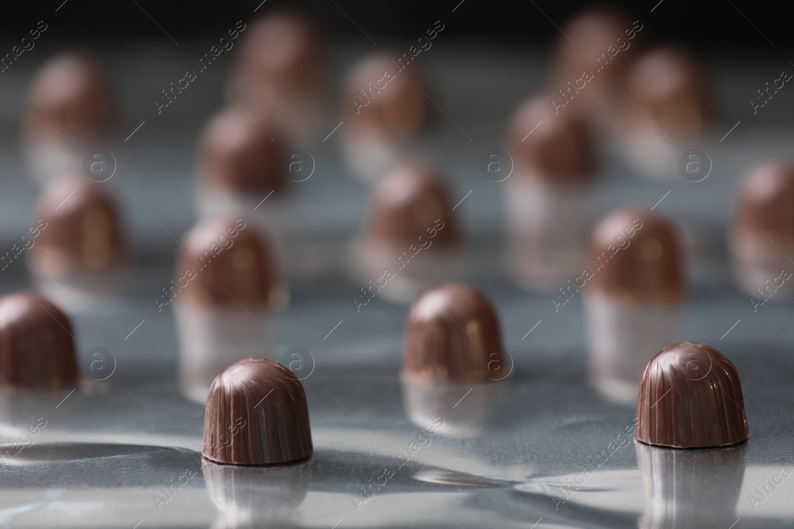 Photo of Many delicious chocolate candies on production line, closeup