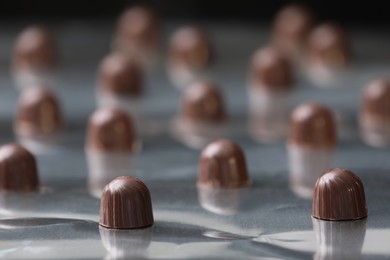 Photo of Many delicious chocolate candies on production line, closeup