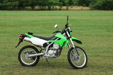 Stylish cross motorcycle on green grass outdoors