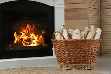 Firewood in wicker basket near fireplace indoors