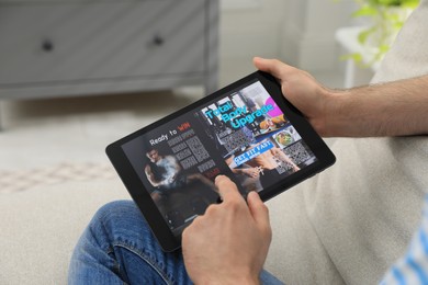 Photo of Man reading online magazine on tablet indoors, closeup