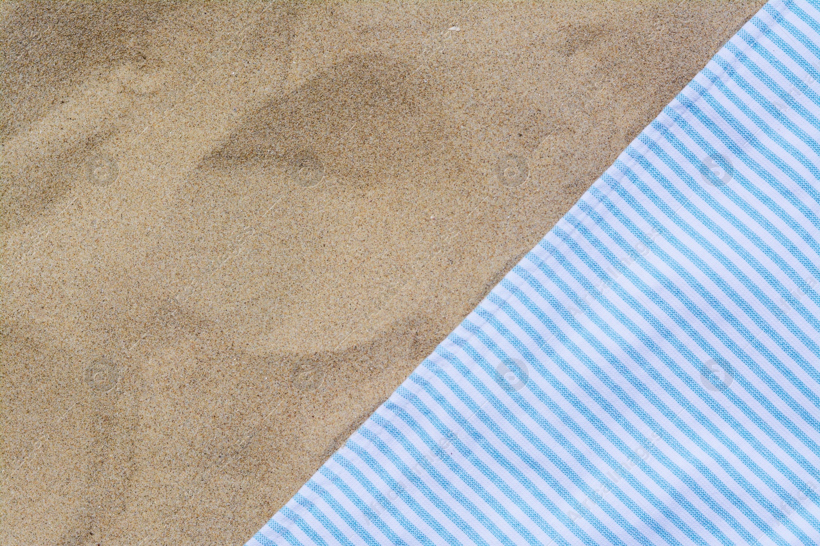 Photo of White and light blue striped towel on sandy beach, top view. Space for text