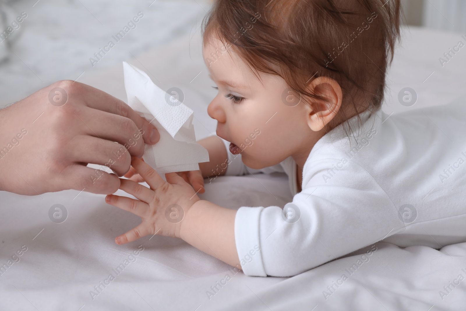 Photo of Father taking care of little baby suffering from runny nose in bed, closeup