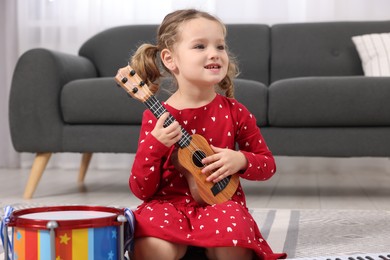 Photo of Little girl playing toy guitar at home