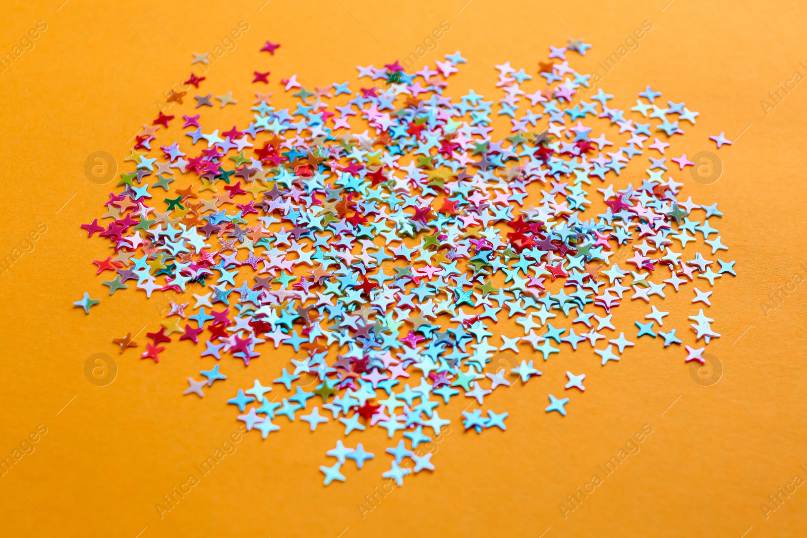 Photo of Shiny bright colorful glitter on pale orange background