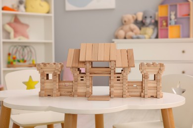 Photo of Wooden entry gate on white table indoors. Children's toy