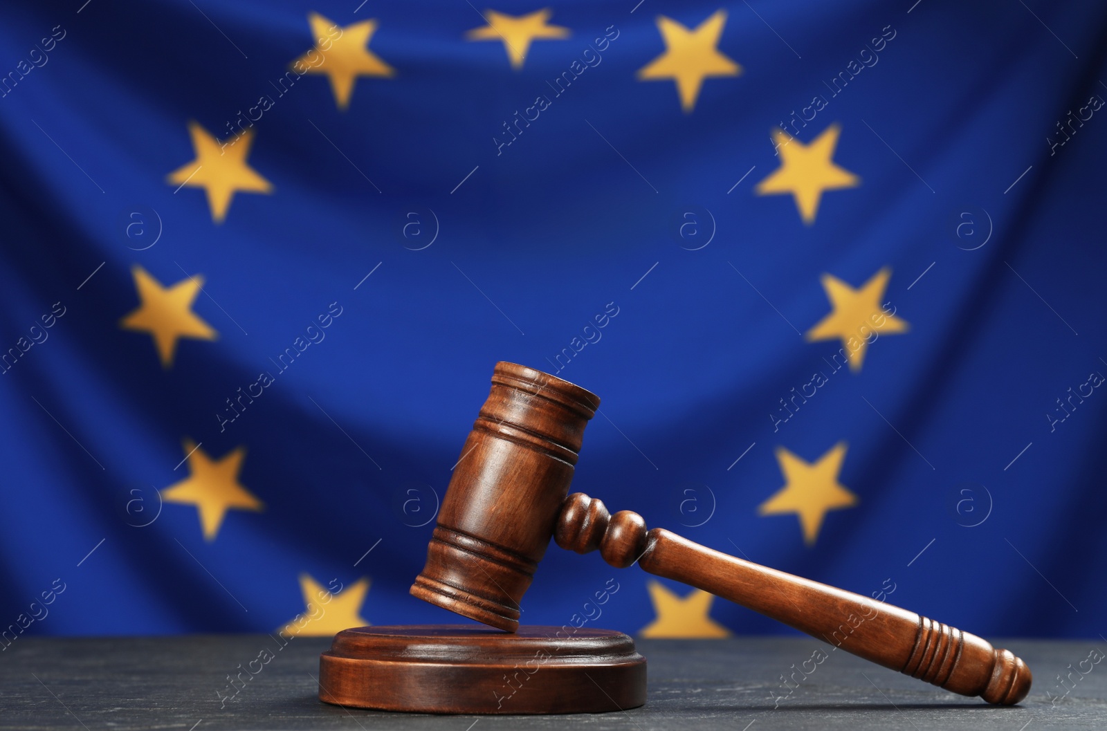 Photo of Judge's gavel on black table against flag of European Union