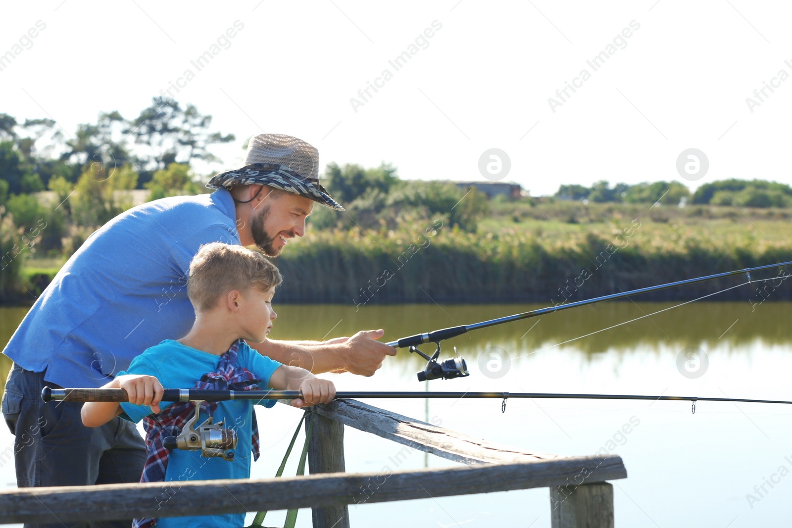 Photo of Father and son fishing together on sunny day