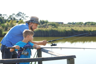 Father and son fishing together on sunny day