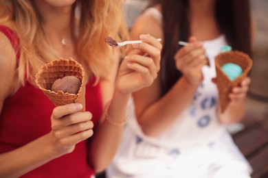 Photo of Young women with ice cream spending time together outdoors, closeup