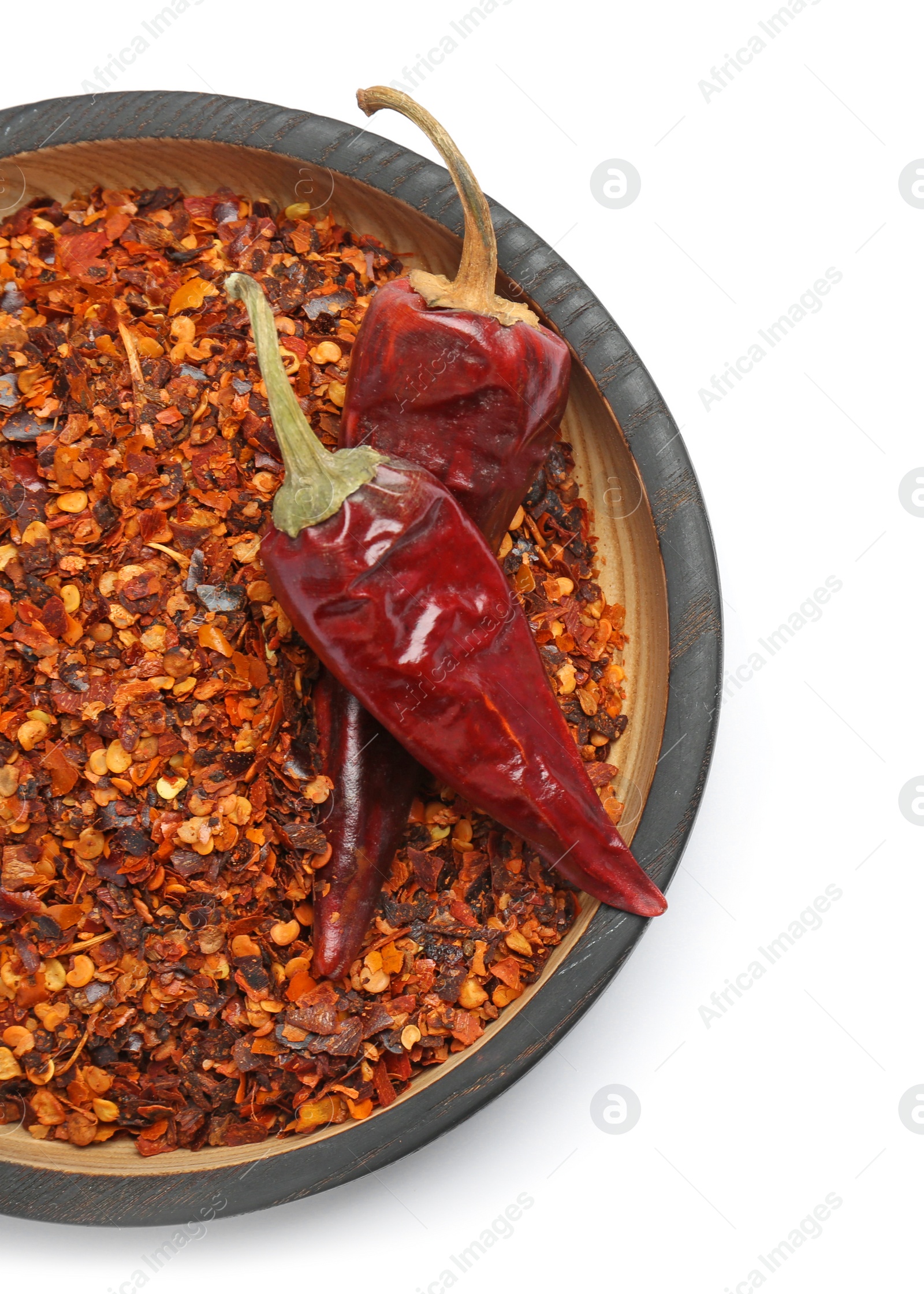 Photo of Plate with crushed chili pepper and pods on white background