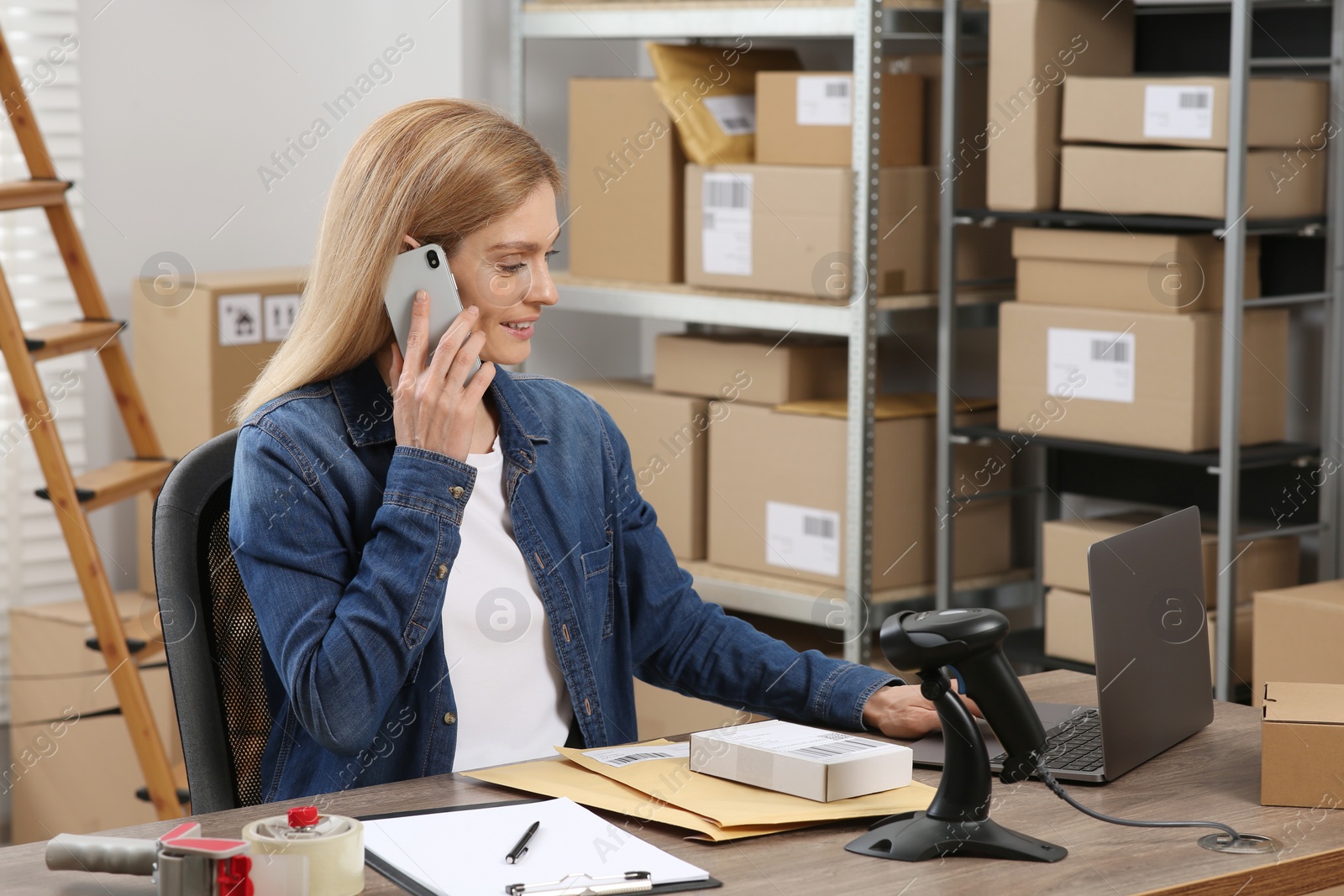 Photo of Seller talking on phone while working in office. Online store