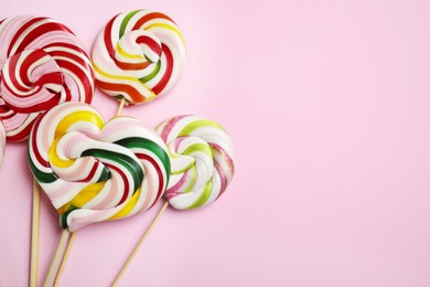 Sticks with different colorful lollipops on pink background, flat lay. Space for text