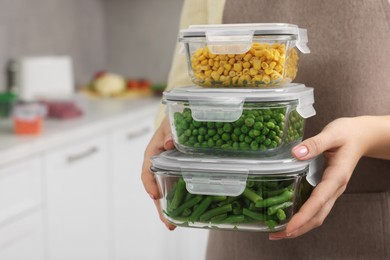 Photo of Woman holding containers with different fresh products in kitchen, closeup and space for text. Food storage