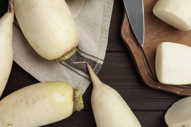 Photo of Raw white turnips on brown wooden table, flat lay