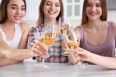 Photo of Beautiful young ladies toasting at home, focus on hands with glasses. Woman's Day