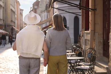 Affectionate senior couple walking outdoors, back view. Space for text