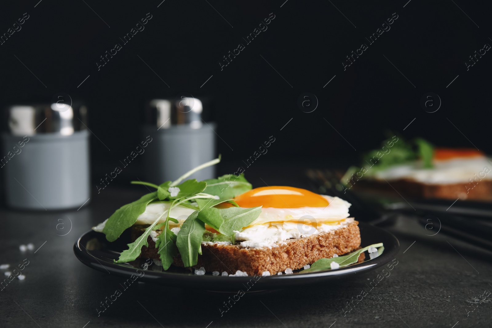 Photo of Delicious sandwich with arugula and fried egg on grey table