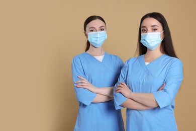 Photo of Nurses wearing protective masks on light brown background, space for text