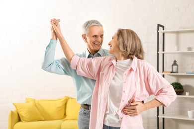 Photo of Happy senior couple dancing together in living room