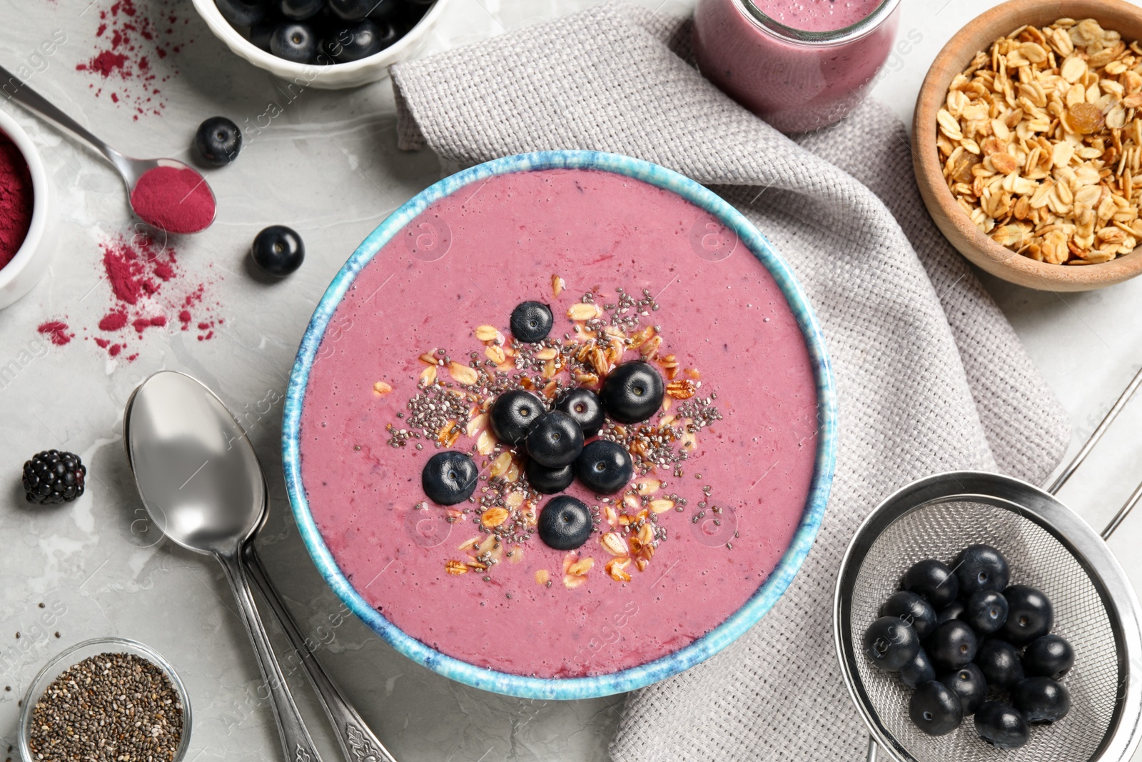 Photo of Delicious acai smoothie with granola and chia seeds served on grey table, flat lay