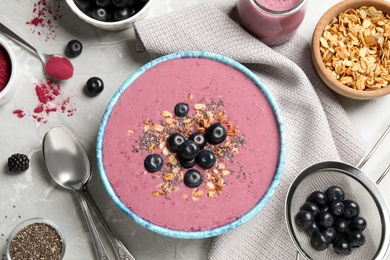 Photo of Delicious acai smoothie with granola and chia seeds served on grey table, flat lay