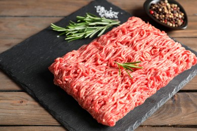 Raw ground meat, spices and rosemary on wooden table, closeup