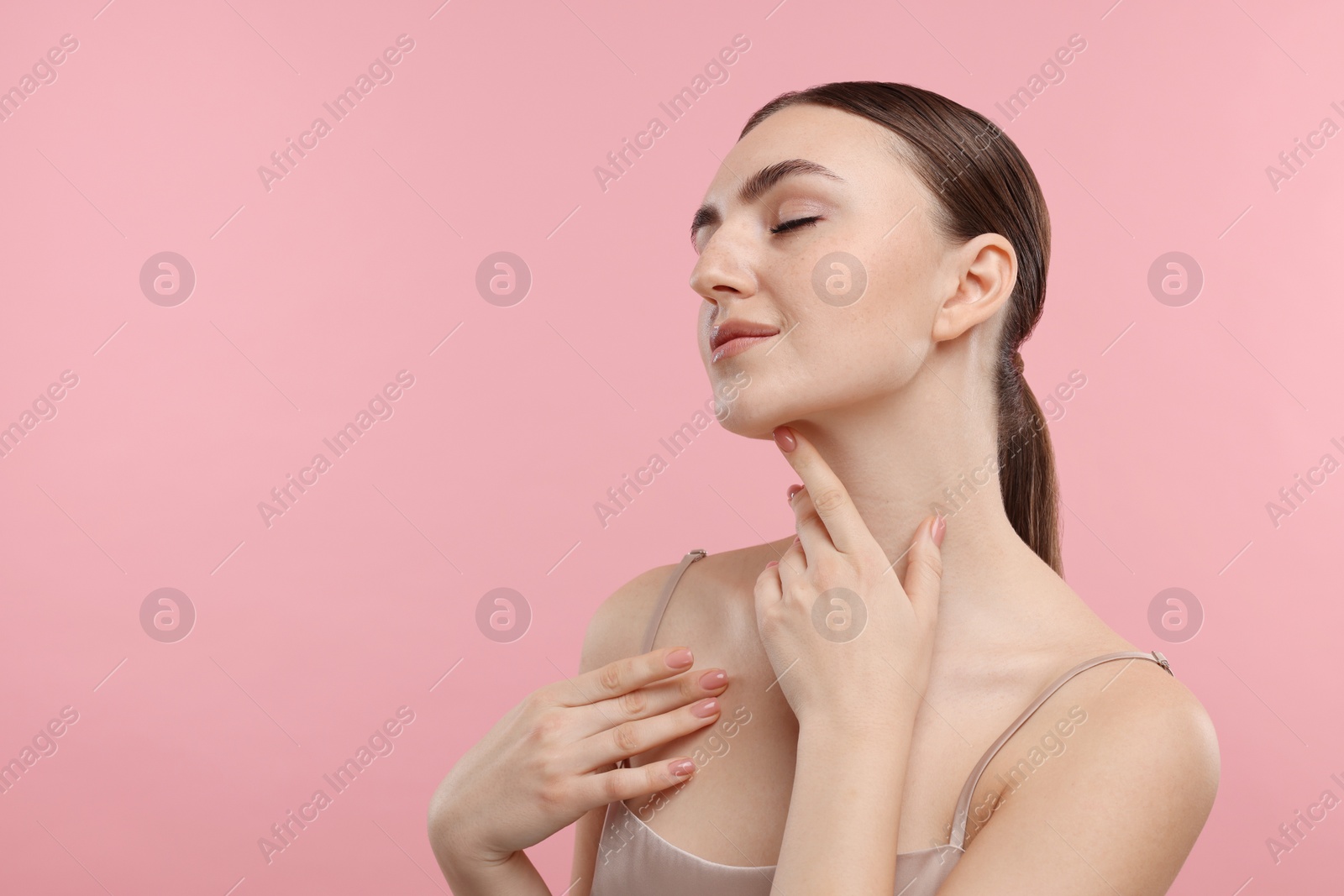 Photo of Beautiful woman touching her neck on pink background. Space for text