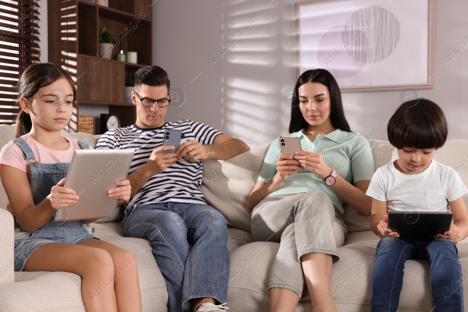 Photo of Internet addiction. Family with different gadgets on sofa at home