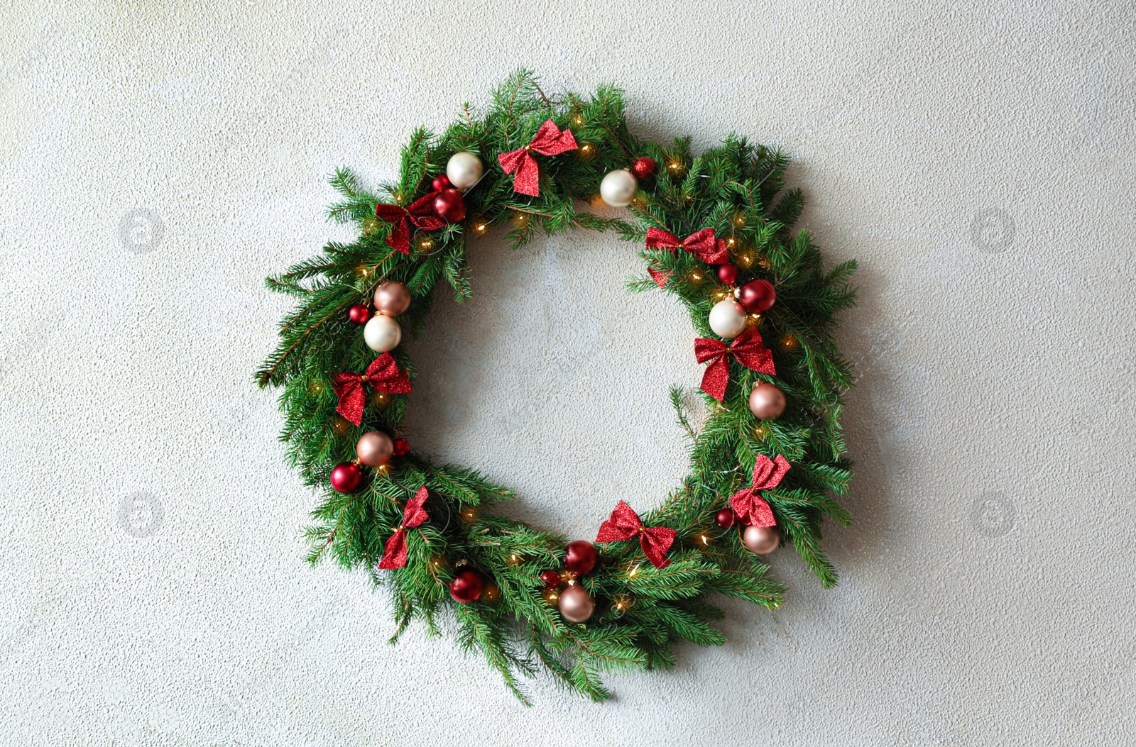 Photo of Beautiful Christmas wreath with festive decor on white wall