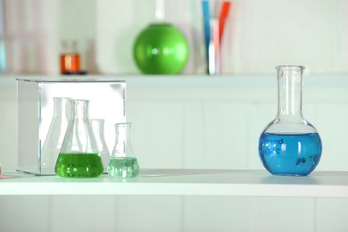 Laboratory analysis. Glass flasks with liquids on white table indoors