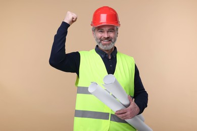 Photo of Architect in hard hat holding drafts on beige background