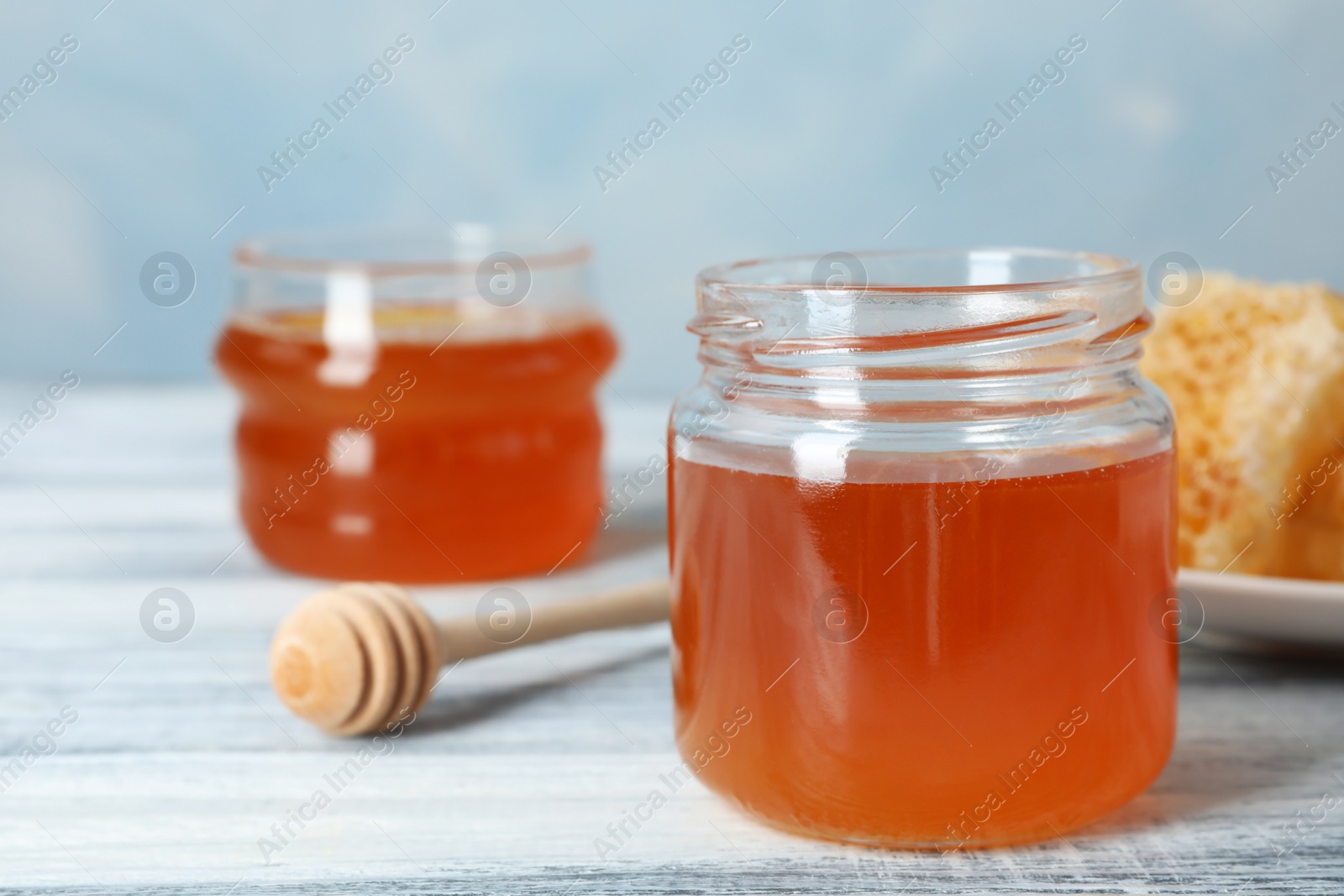Photo of Glass jar with sweet honey and dipper on table, closeup