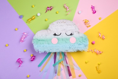 Cloud shaped pinata, streamers and soft balls on color background, flat lay