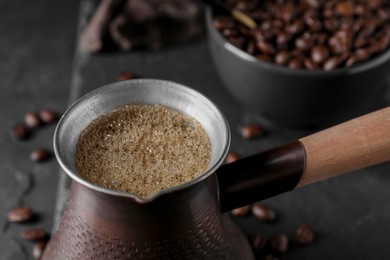 Photo of Cezve with Turkish coffee on dark grey table, closeup
