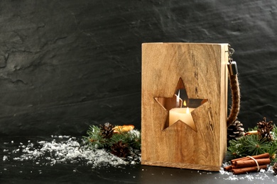 Photo of Wooden Christmas lantern with burning candle and festive decor on black background. Space for text