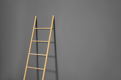 Photo of Modern wooden ladder on grey background. Space for text