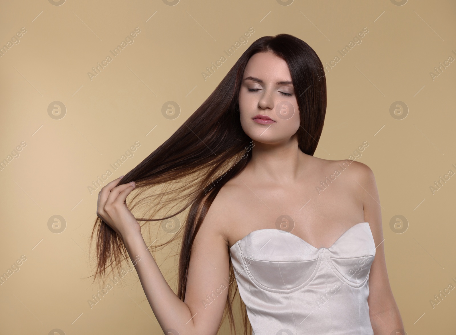 Photo of Portrait of beautiful young woman with healthy strong hair on beige background