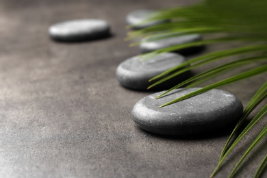 Photo of Spa stones and green leaf on grey background. Space for text