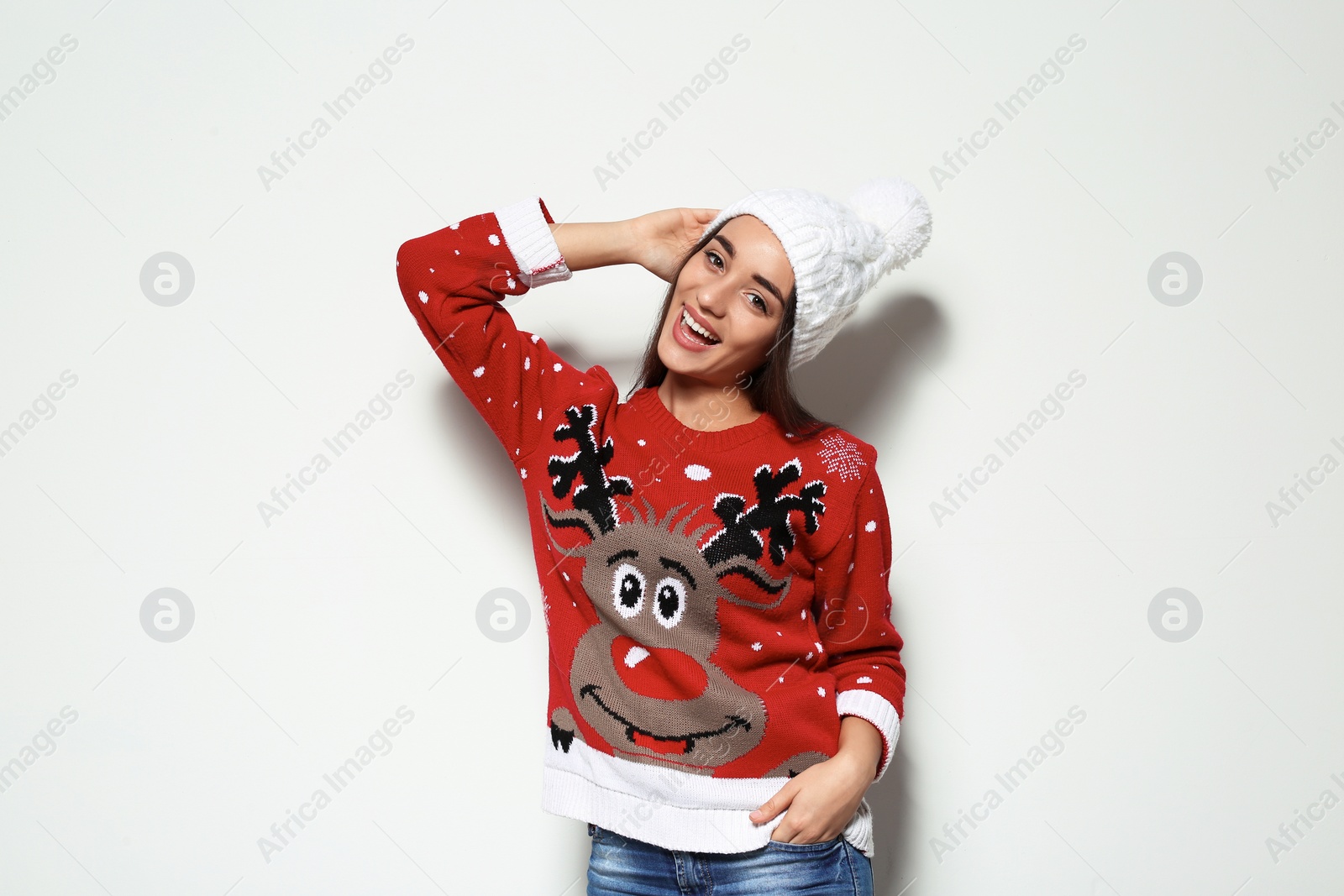 Photo of Young woman in Christmas sweater and knitted hat on white background