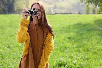 Photo of Woman taking photo with camera on green meadow