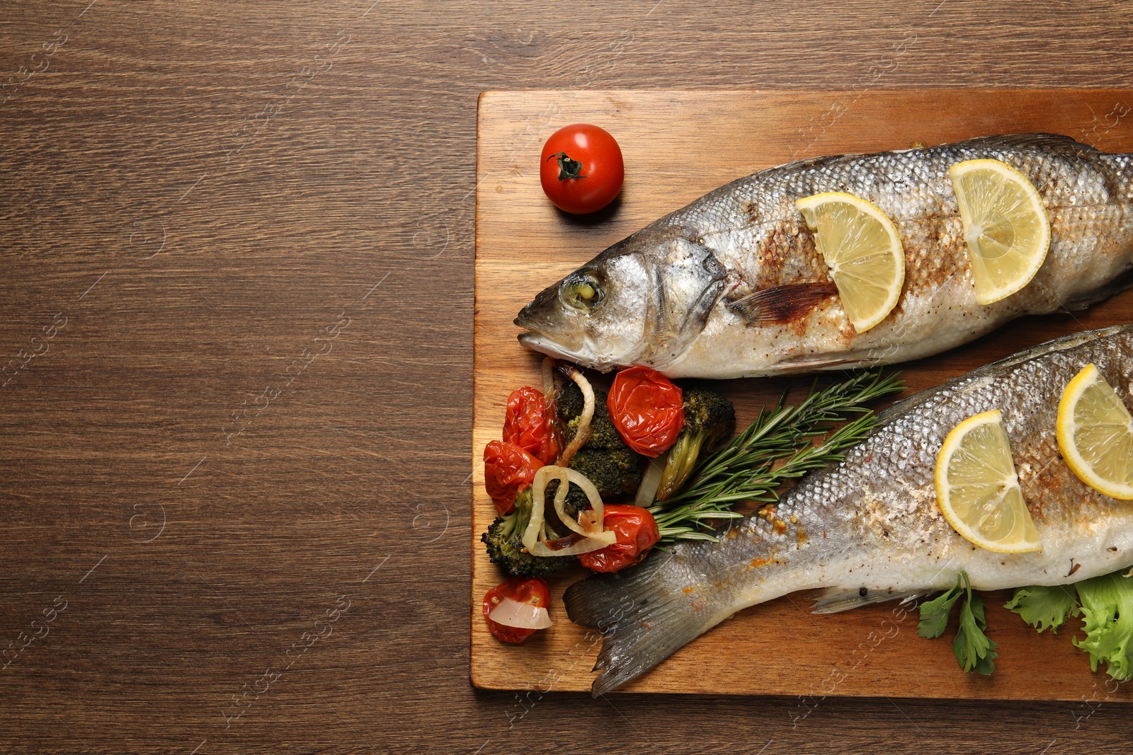 Photo of Delicious baked fish and vegetables on wooden table, top view. Space for text