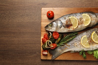 Photo of Delicious baked fish and vegetables on wooden table, top view. Space for text