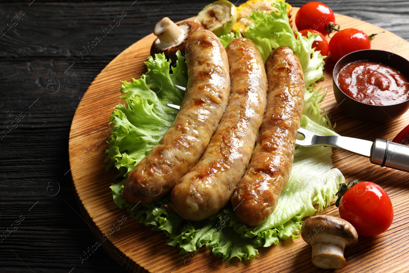 Photo of Delicious sausages and vegetables served for barbecue party on wooden table