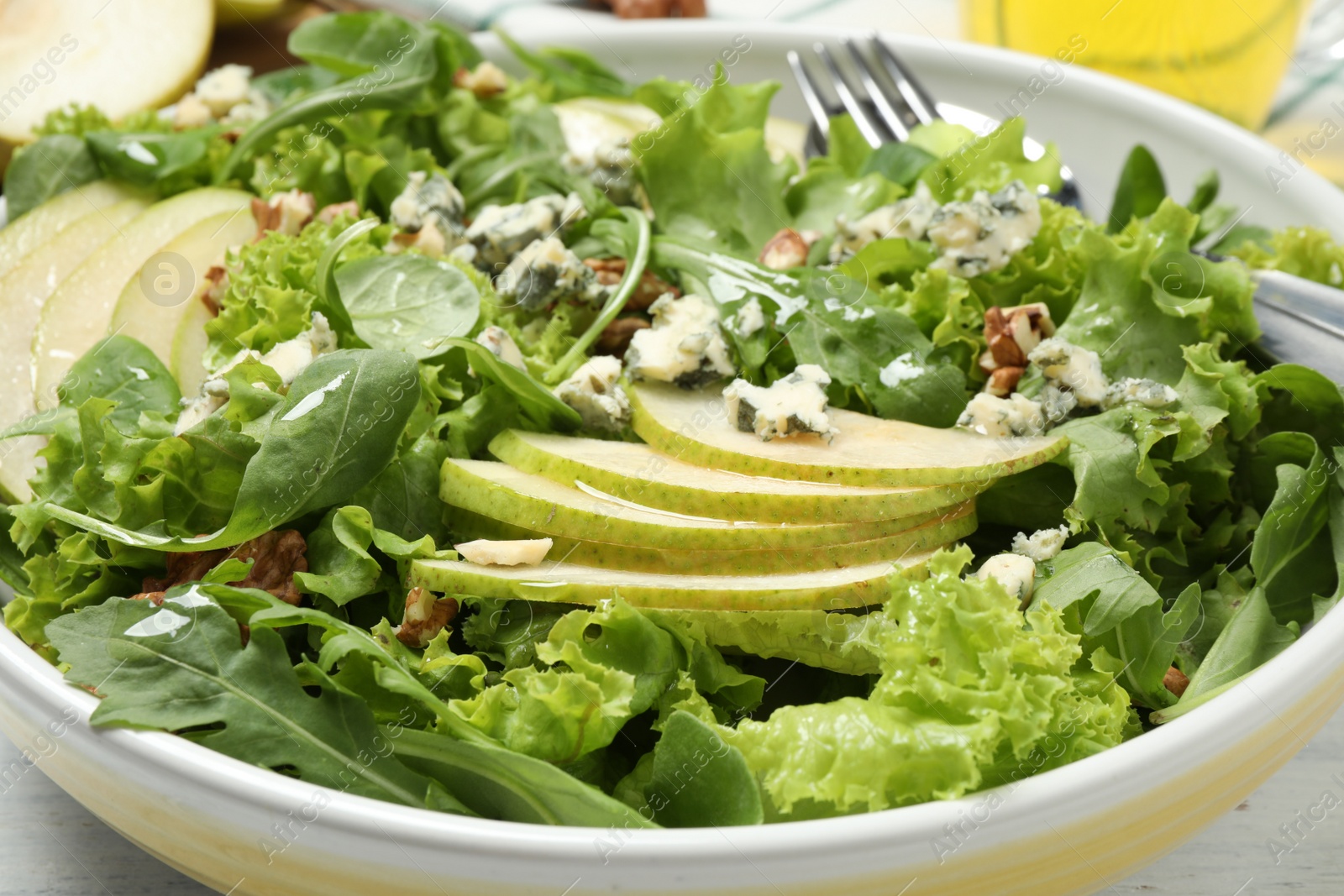 Photo of Fresh salad with pear slices in bowl, closeup